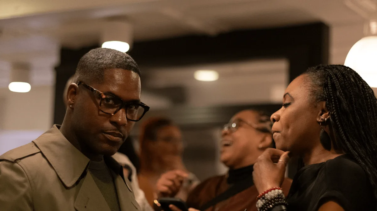 Candid guests in conversation at an indoor social event.